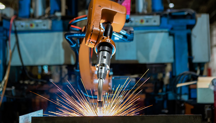 On-site robotic welding solution machine in a dark, industrial area with sparks flying. 