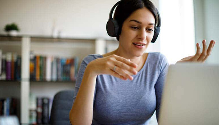 A woman sitting before a laptop translating live audio for multilingual streaming.