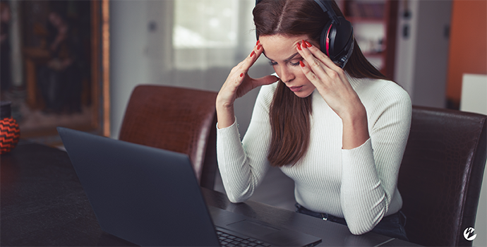A woman in front of her laptop with an expression of frustration.