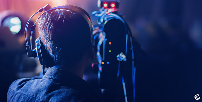 Blue-tinted image of someone filming with a camera